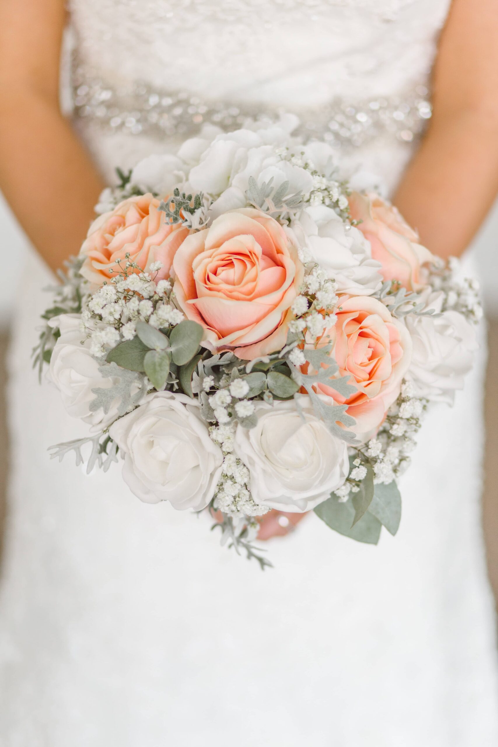A close-up shot of a bride holding her bouquet of pink and white roses
