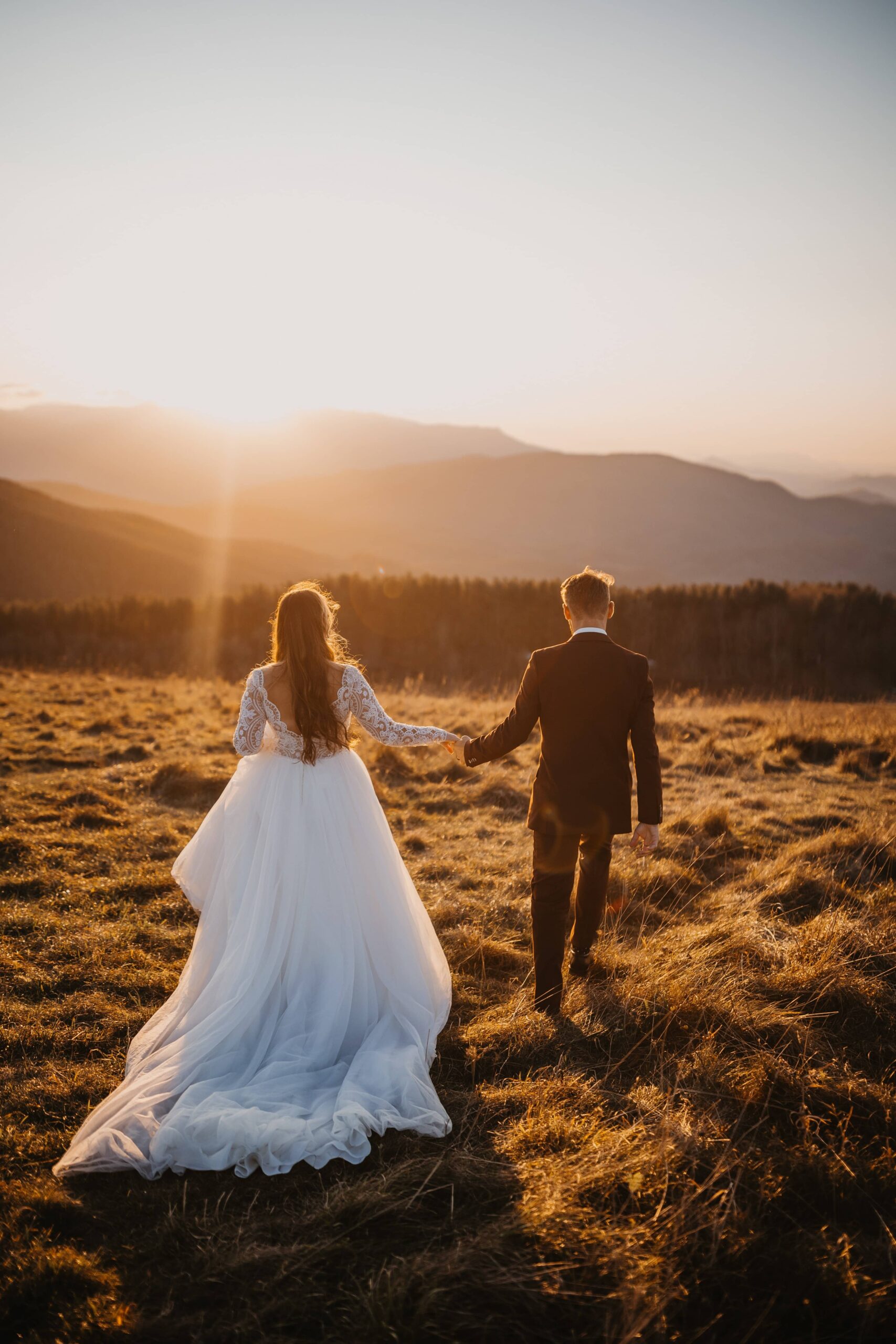A bride and groom running together into the sunset